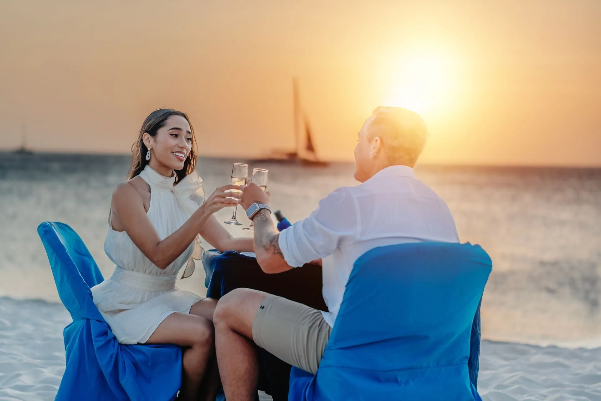 Couple toasting at a beach table at sunset