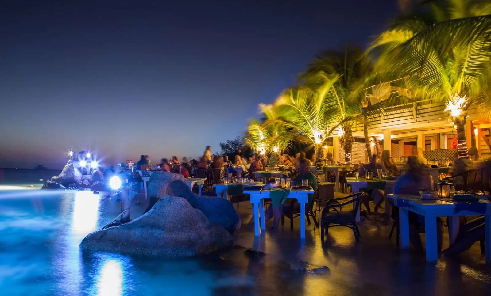 Beach tables lit at night by the water