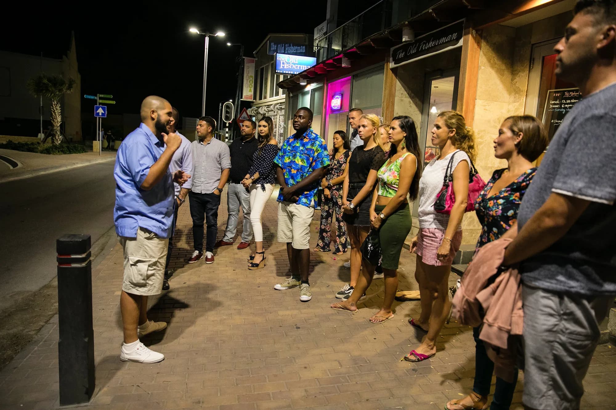 Guide addressing a tour group on a downtown street at night