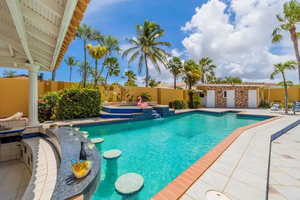 Villa pool with swim-up bar seating and palm trees